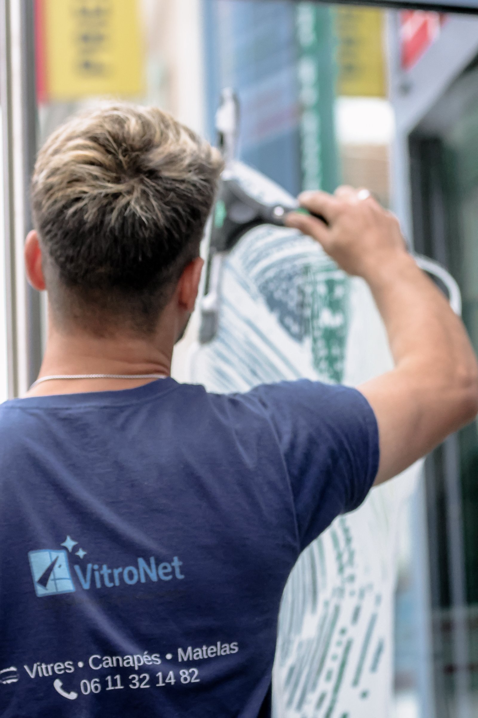 Technicien VitroNet nettoyant une baie vitrée à domicile